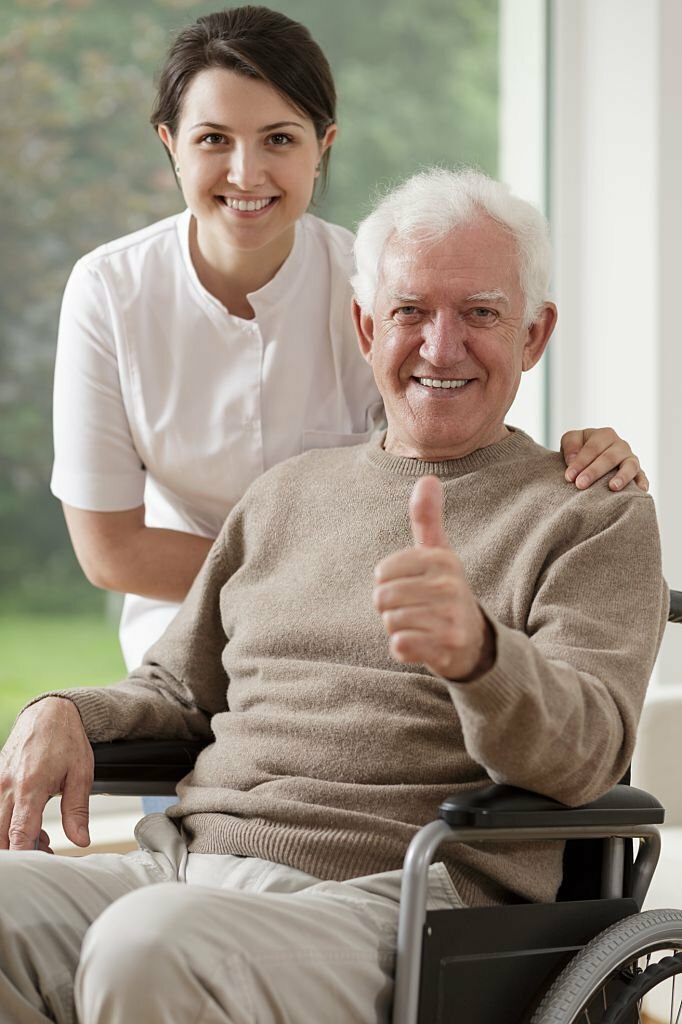 Picture of smiling old man sitting on wheelchair and carer